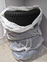 Stack of four tires wrapped in bags