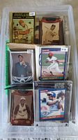 Overall view of plastic box filled with assorted sports trading cards, sleeved cards visible on top
