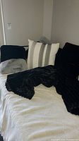 Throw blanket and pillows arranged on bed