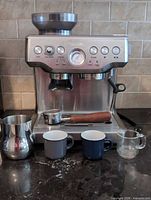 Front view of Breville espresso machine with accessories arranged in front