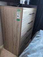 Side view of light oak five-drawer dresser showing black pulls and laminate finish
