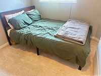 Full bed assembled showing bedding, frame legs and headboard