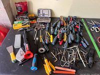 Overview of entire lot on table showing hand tools, bit sets and fastener strips