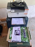 Printer with power cord on top, reference guide and paper ream beneath
