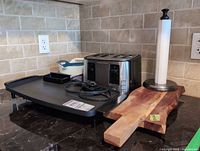 Lot overview showing griddle, toaster, bowls, board, paper towel holder
