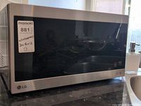 Front view of stainless steel LG microwave with black glass door