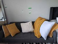 Sofa with two mustard pillows, cream faux-fur pillow, white pillow, mustard throw blanket