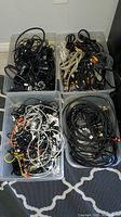 Four tubs filled with mixed cables and adapters