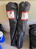 Two folded Outbound chairs in carry bags leaning against wall