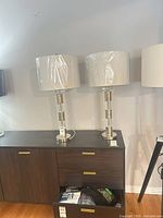 Pair of chrome and acrylic table lamps on cabinet