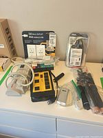 Lot overview showing power bars, packaged USB outlet, outdoor timer, flashlights, cables