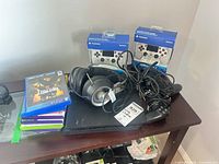 Top view of PS4 Slim, loose controller, boxed white controllers, headset, stack of game cases