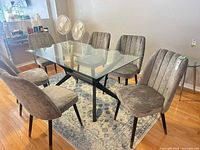 Six grey velvet dining chairs around glass table showing full set