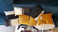 All six pillows displayed on sofa: three mustard square cushions, three patterned lumbar cushions