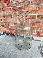 Full view of clear glass carboy standing upright