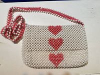 Front view of Isaac Mizrahi white and pink beaded heart crossbody bag with strap