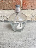 Front view of clear glass Lampe Berger lamp showing cap and wick