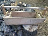 Full view of wooden toolbox on logs showing handle and rectangular body