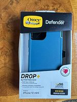 Front of boxed OtterBox Defender DROP+ teal case