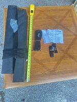 All components laid on table: foam blocks in mesh sleeve, tape measure alongside, rolled long strap, short cam buckle straps, instruction sheet