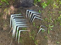 Group of 17 white metal shelf brackets spread on ground