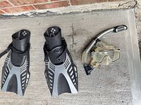 Pair black/gray fins, mask, snorkel on concrete