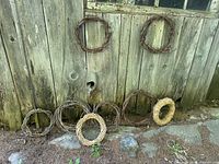 Eight wreaths leaning against wooden wall showing materials and sizes