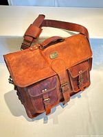 Front view of Cuero leather messenger bag showing flap, buckles, pockets, shoulder strap