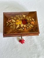 Closed jewelry box top showing floral marquetry and tasselled key