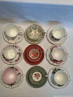 Nine teacups and saucers top-view showing interior colours and patterns