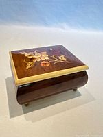 Closed music box showing marquetry floral lid and brass feet