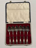 Open presentation case showing six silver-plated teaspoons in red velvet insert