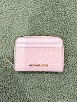 Front view of pink Michael Kors wallet showing logo plaque and card slots
