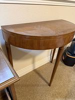 angled view of console table showing half-round top, wood grain, leg detail