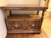 Cabinet closed showing carved doors, brass pulls, turned supports