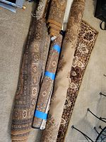 Four rolled oriental area rugs on carpeted floor
