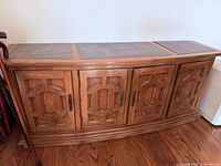 Full view of sideboard showing four doors, leather top insets, carved panels, bowed base