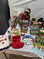 assorted Christmas ornaments, tins, stocking, plush, napkins, candles displayed on table
