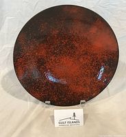 Front view of red and black speckled enamel plate on stand