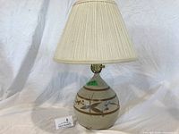 Front view of lamp showing ceramic body decoration and shade
