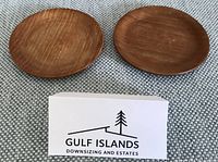 Two round teak coasters placed side by side on fabric mat with size reference card