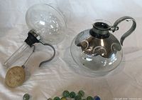 Upper and lower glass globes, metal collar, filter and marbles displayed
