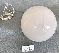 White opaline glass globe shade with cord coiled beside