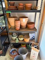 Full shelving view showing terracotta pots, ceramic planters, buckets, NOMA box, stakes