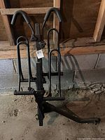 front view of folded hitch-mount bicycle rack showing padded hooks and wheel trays