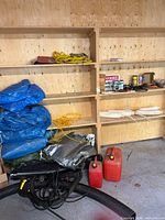 Wide view of shelving with tarps, rope, fuel cans, fenders, tools and supplies