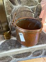 Copper bucket with brass ladle on stone hearth