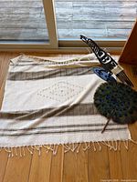 Overall view of textile laid on floor with bird sculpture and fan