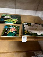 All three ceramic tiles on shelf showing relative sizes and motifs