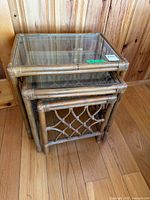 Three rattan nesting tables stacked showing glass top and lattice sides
